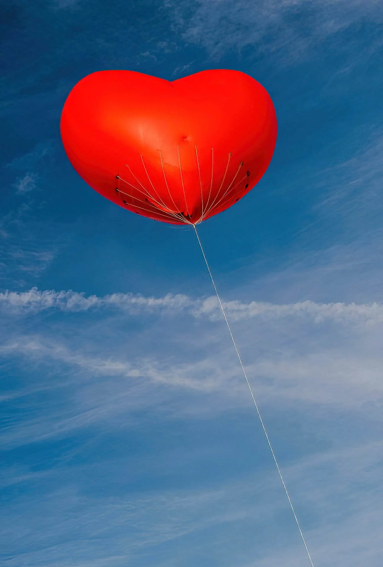 Red heart-shaped balloon floating in the sky