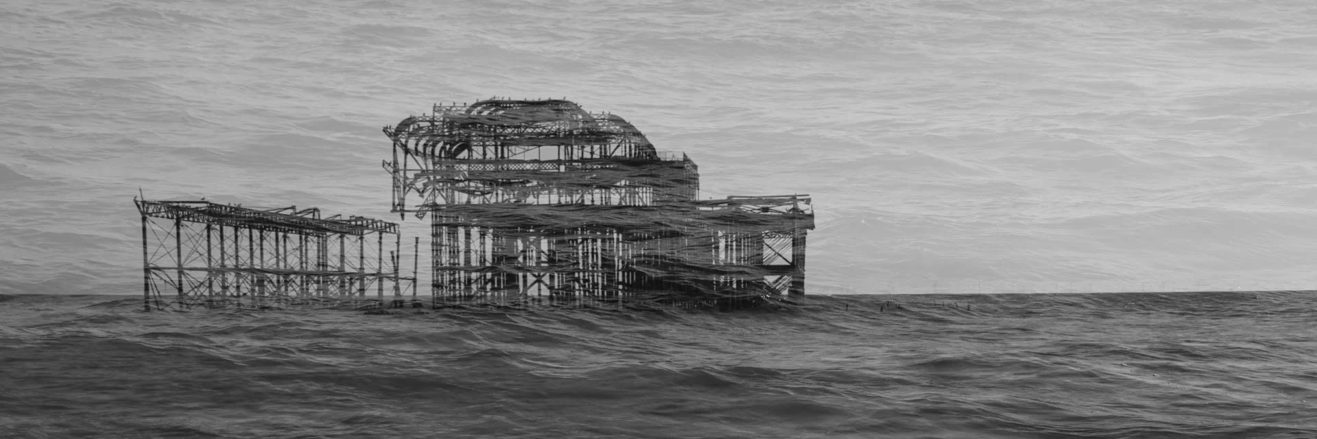 Black and white photo of a dilapidated pier structure in the ocean.