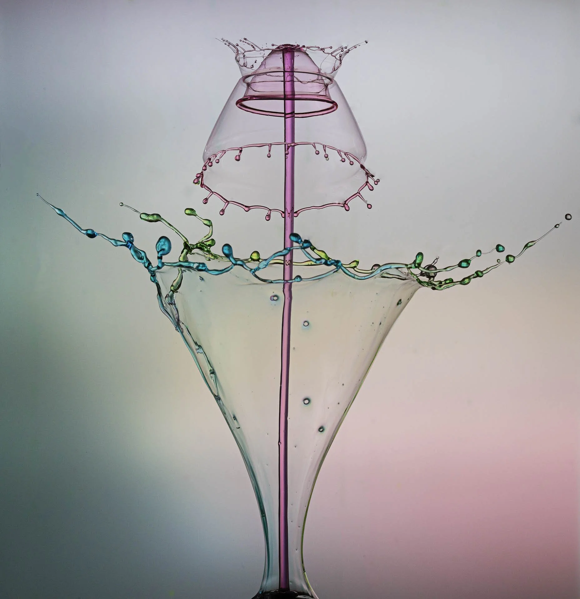 High-speed photograph of colorful liquid splash collision, creating an intricate, symmetrical pattern with droplets suspended in mid-air against a gradient background.