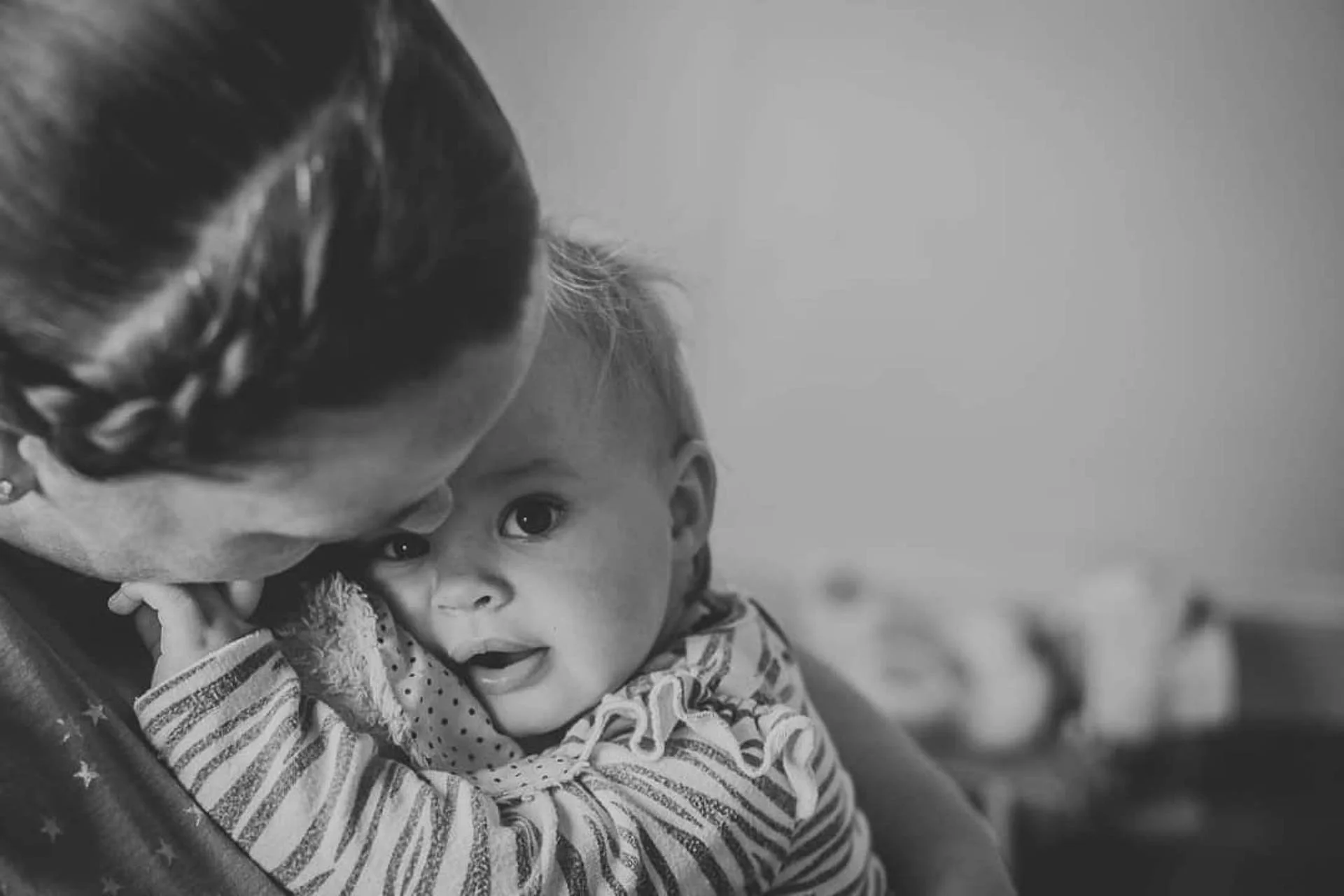 Black and white photo of a person hugging a baby, showing affection and tenderness.