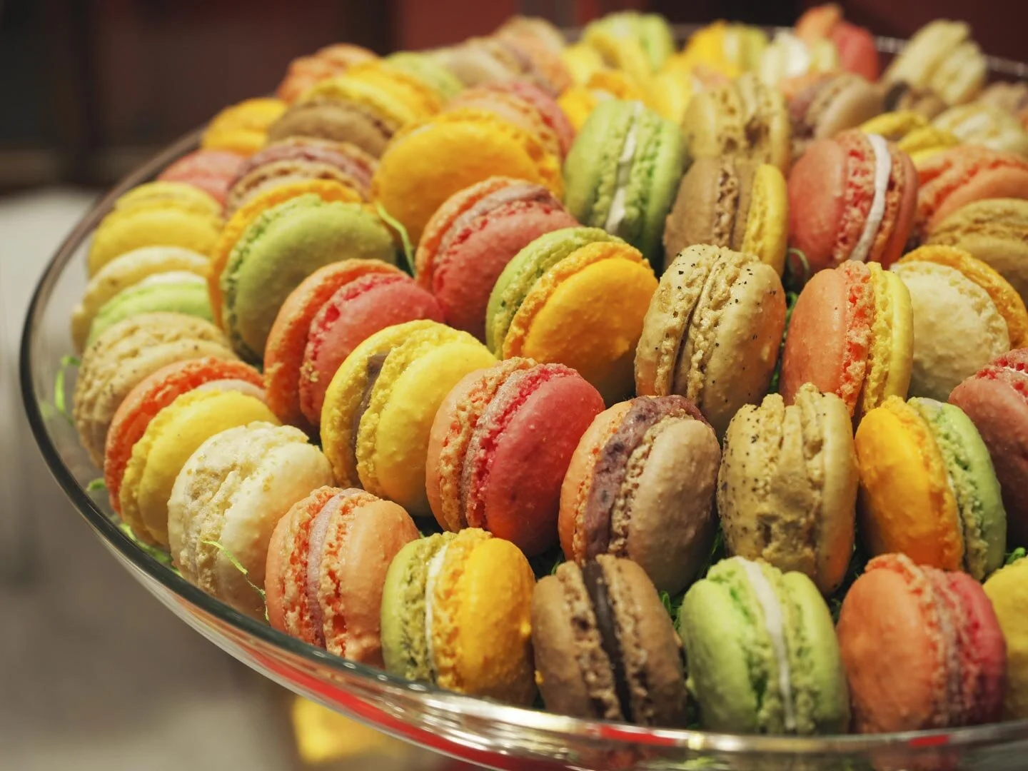 Assorted colorful macarons in a glass dish