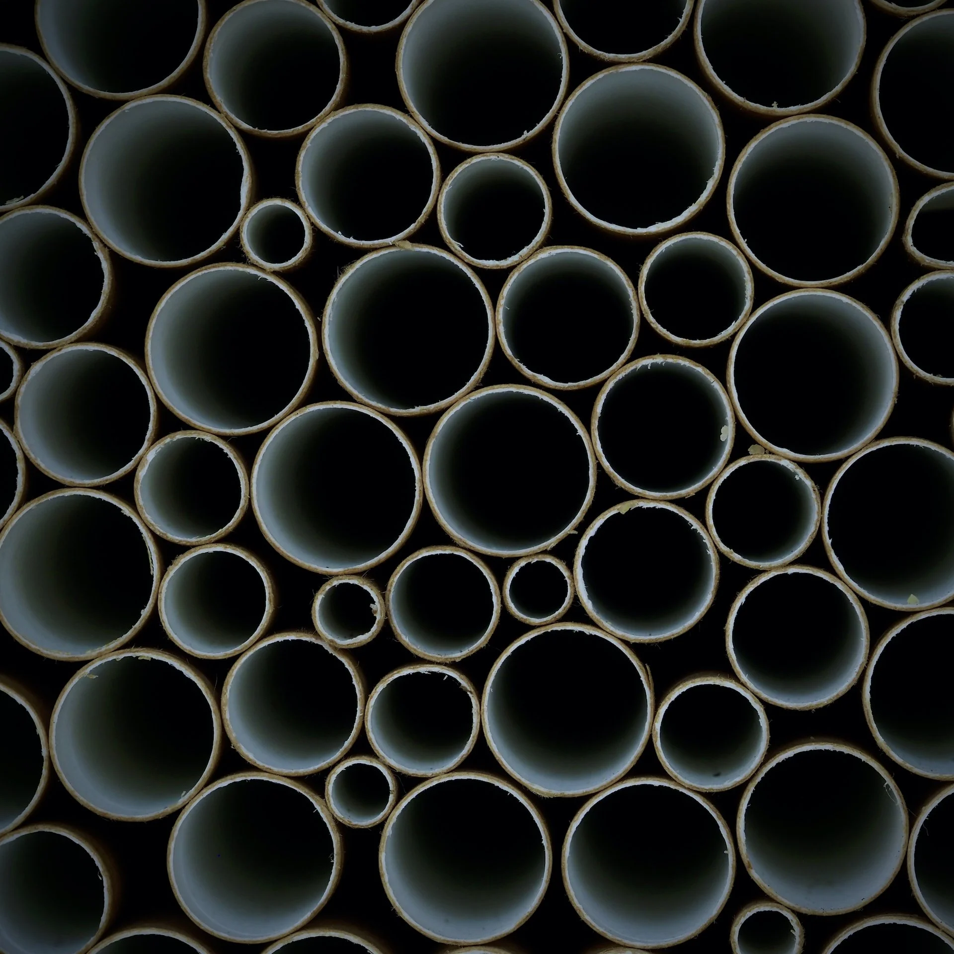 Close-up of various-sized PVC pipes stacked vertically.