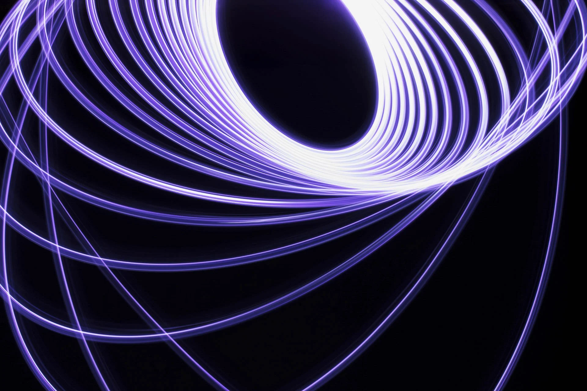 Abstract background with swirling purple light trails on a black backdrop.
