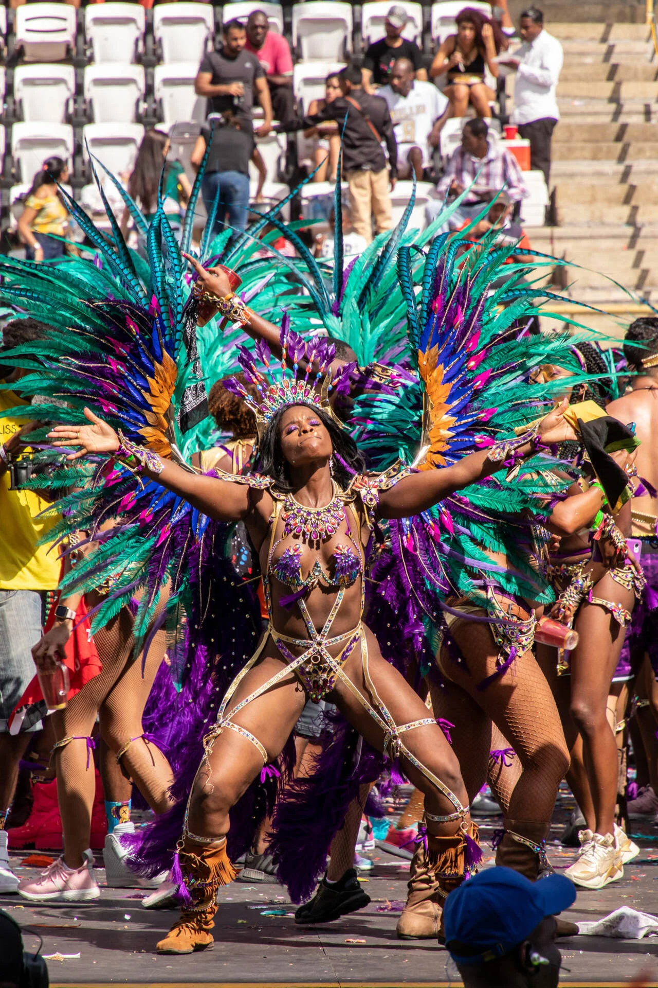 Carnival dancers in vibrant feathered costumes performing in front of an audience.