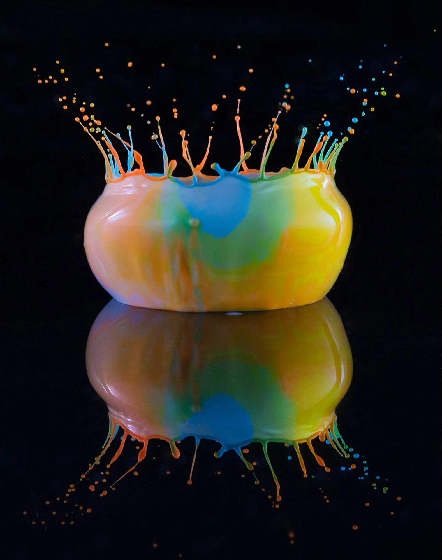 Colorful paint splash on black background with reflection.