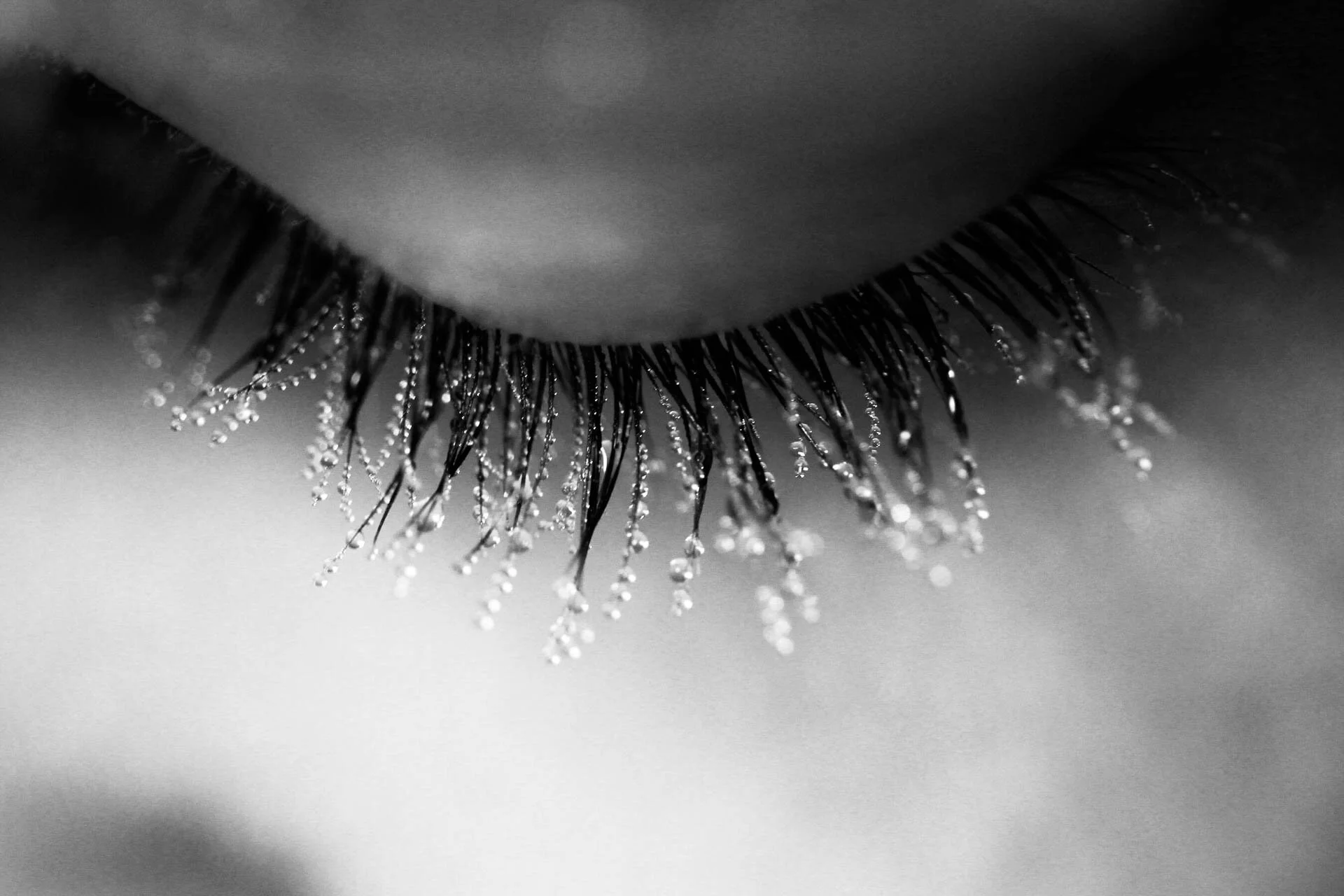 Close-up of closed eye with water droplets on eyelashes.