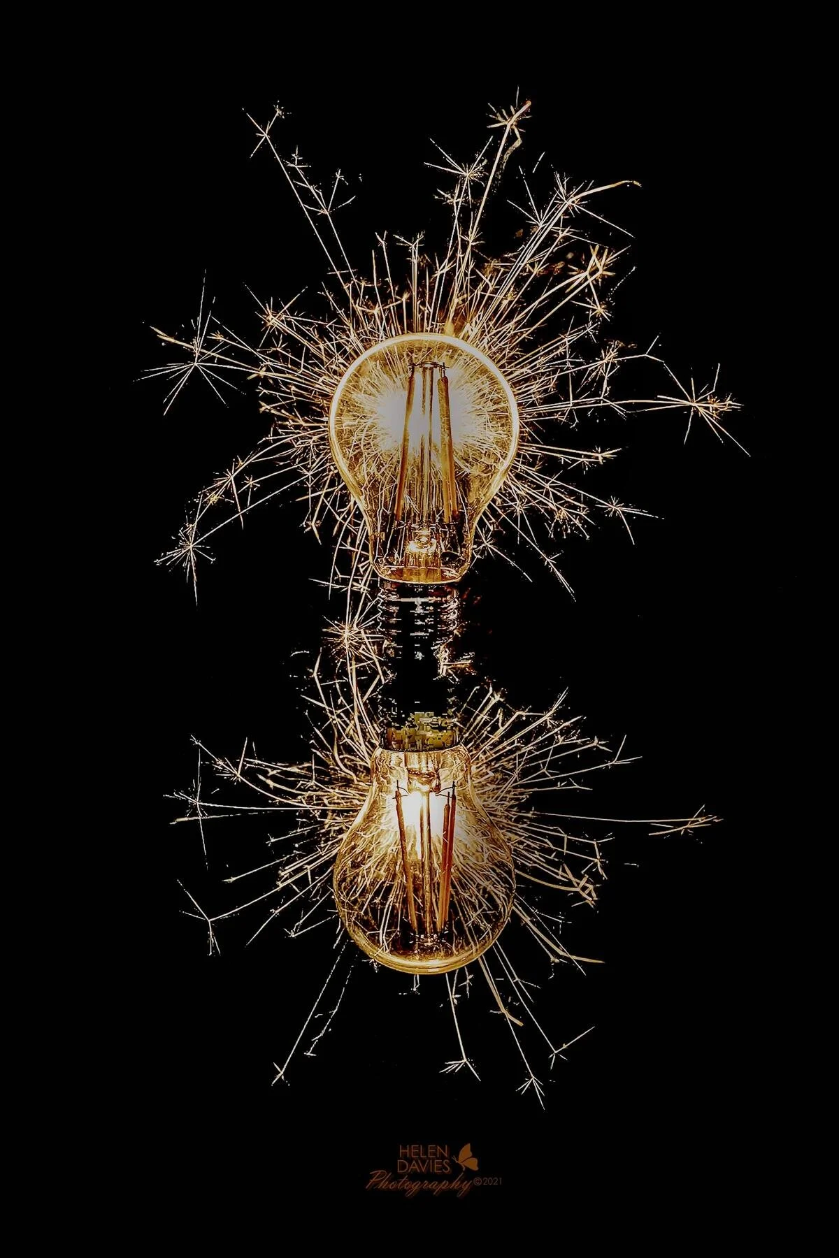 Light bulbs with sparklers on black background, creating a festive visual effect.