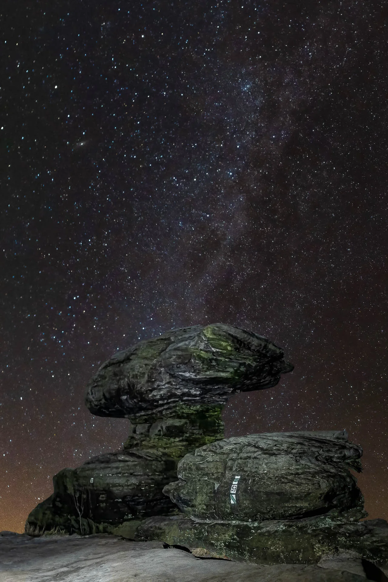 Rock formations under a starry night sky with the Milky Way visible.