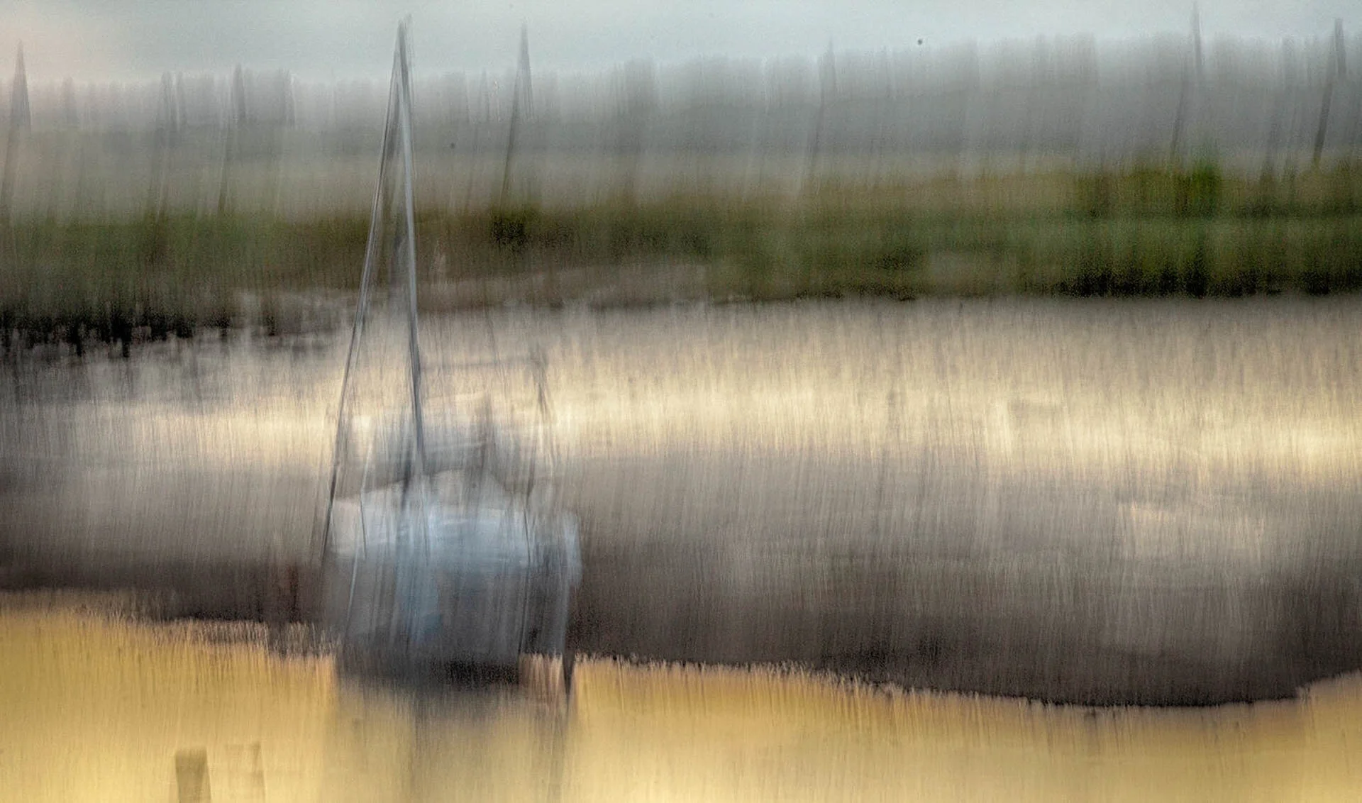 Abstract image of a sailboat on water with blurred motion effect, creating a painterly appearance with muted colors.