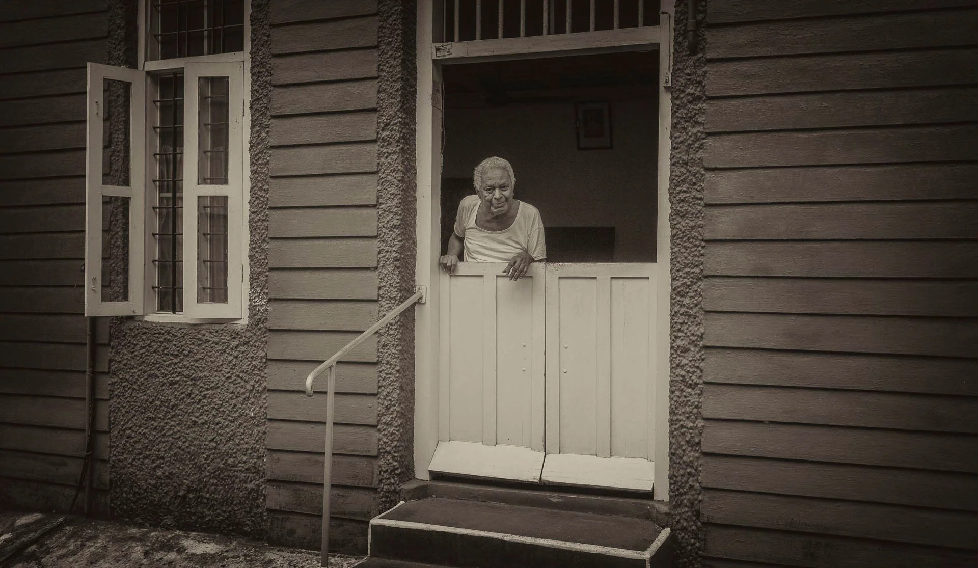 Elderly person looking out from a Dutch door in a wooden house