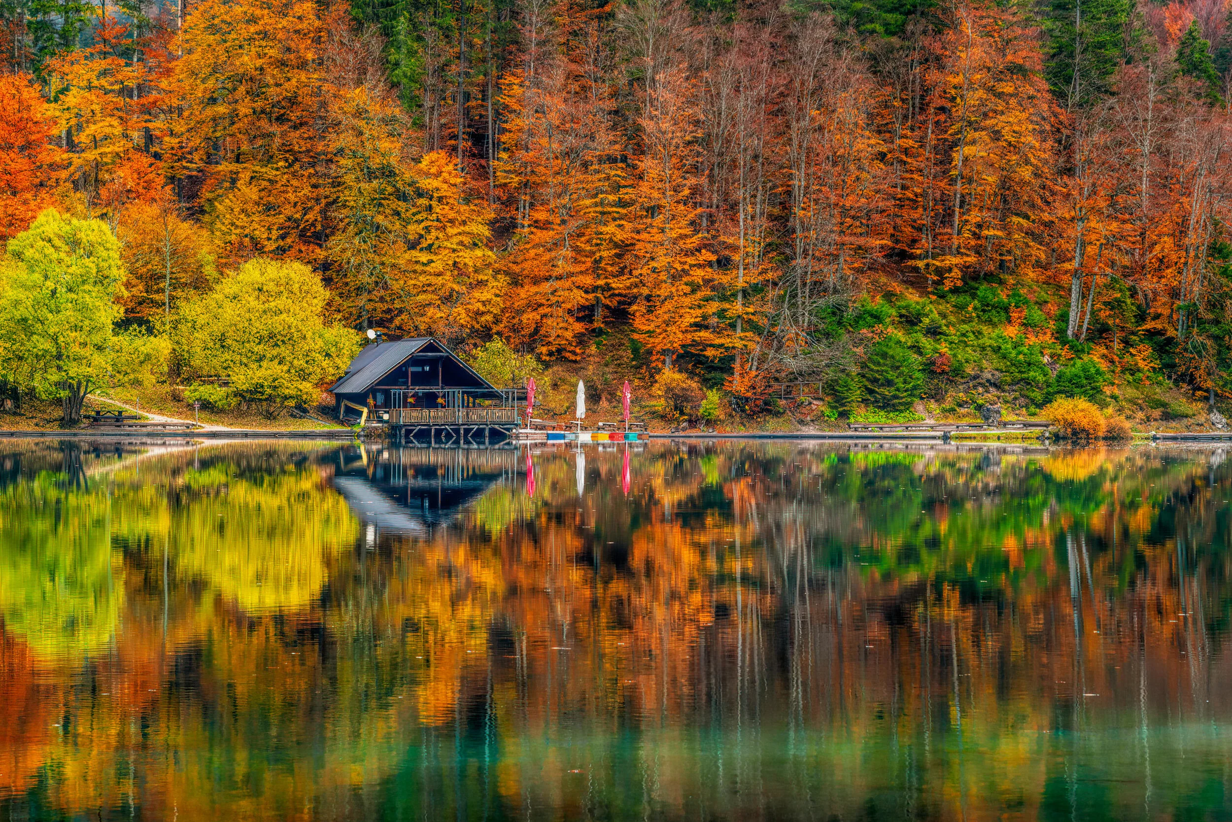 Cozy cabin by a lake with autumn trees reflected in the water