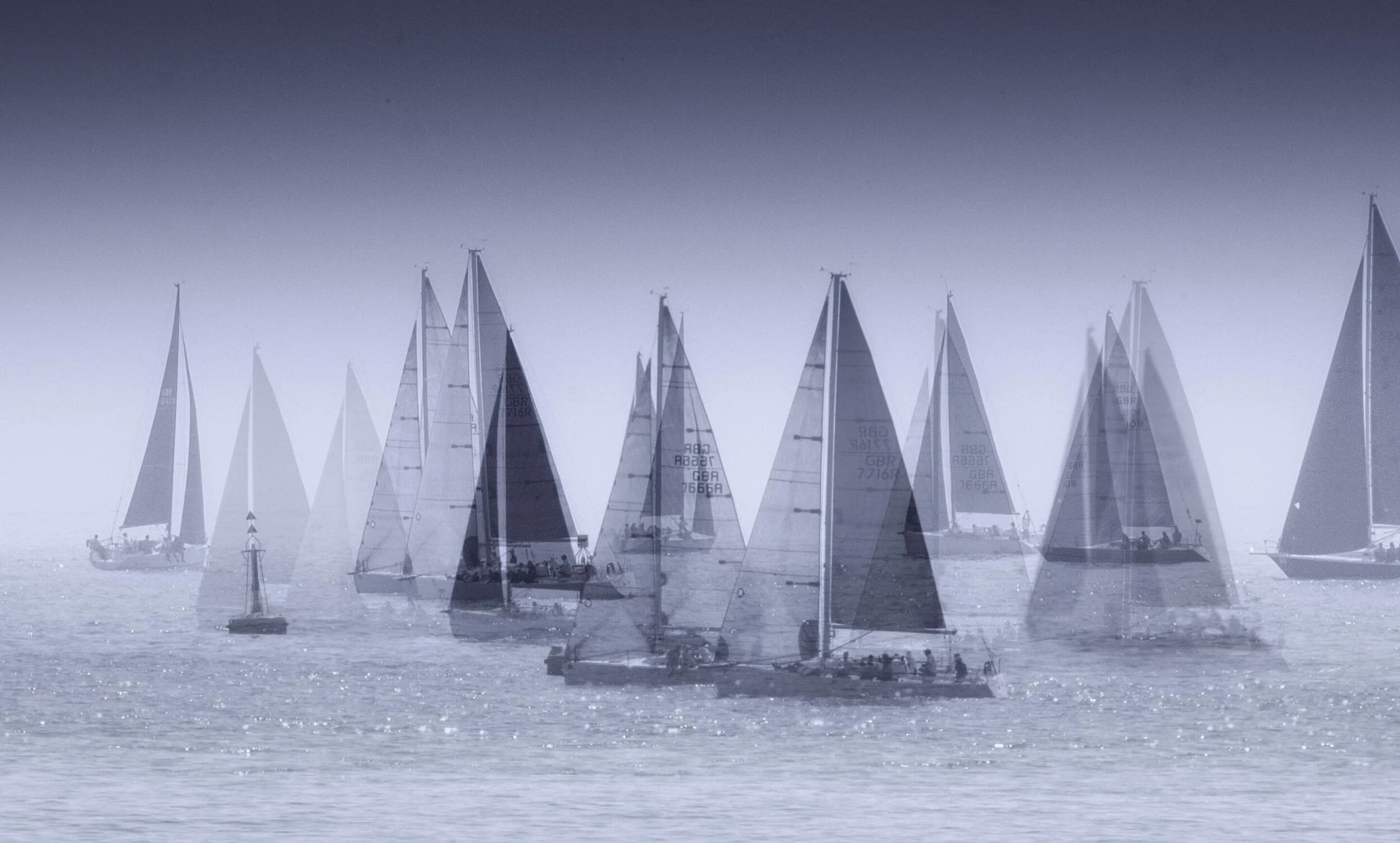 Sailboats in a foggy sea during a regatta.