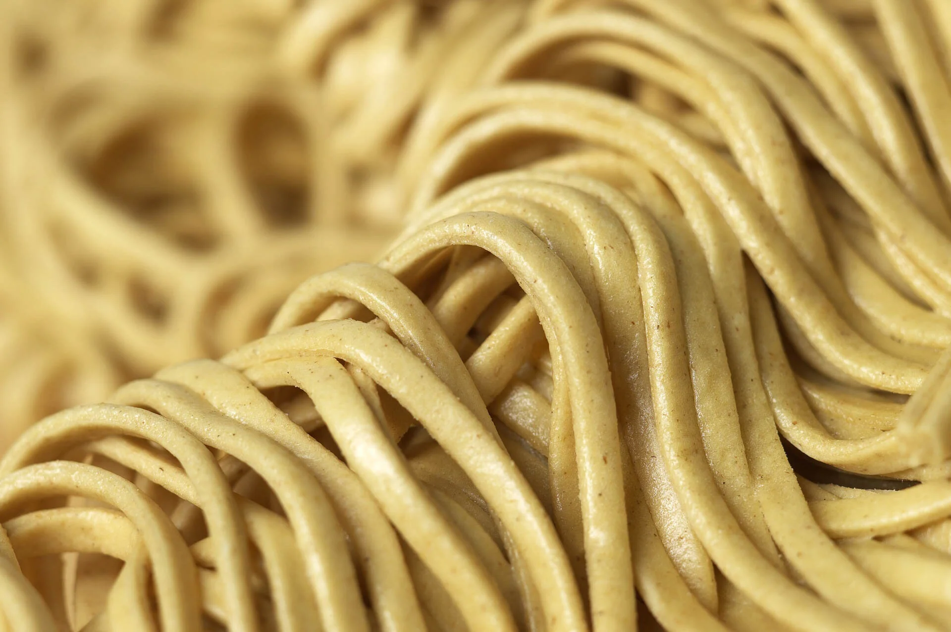 Close-up of uncooked yellow noodles in a heap.