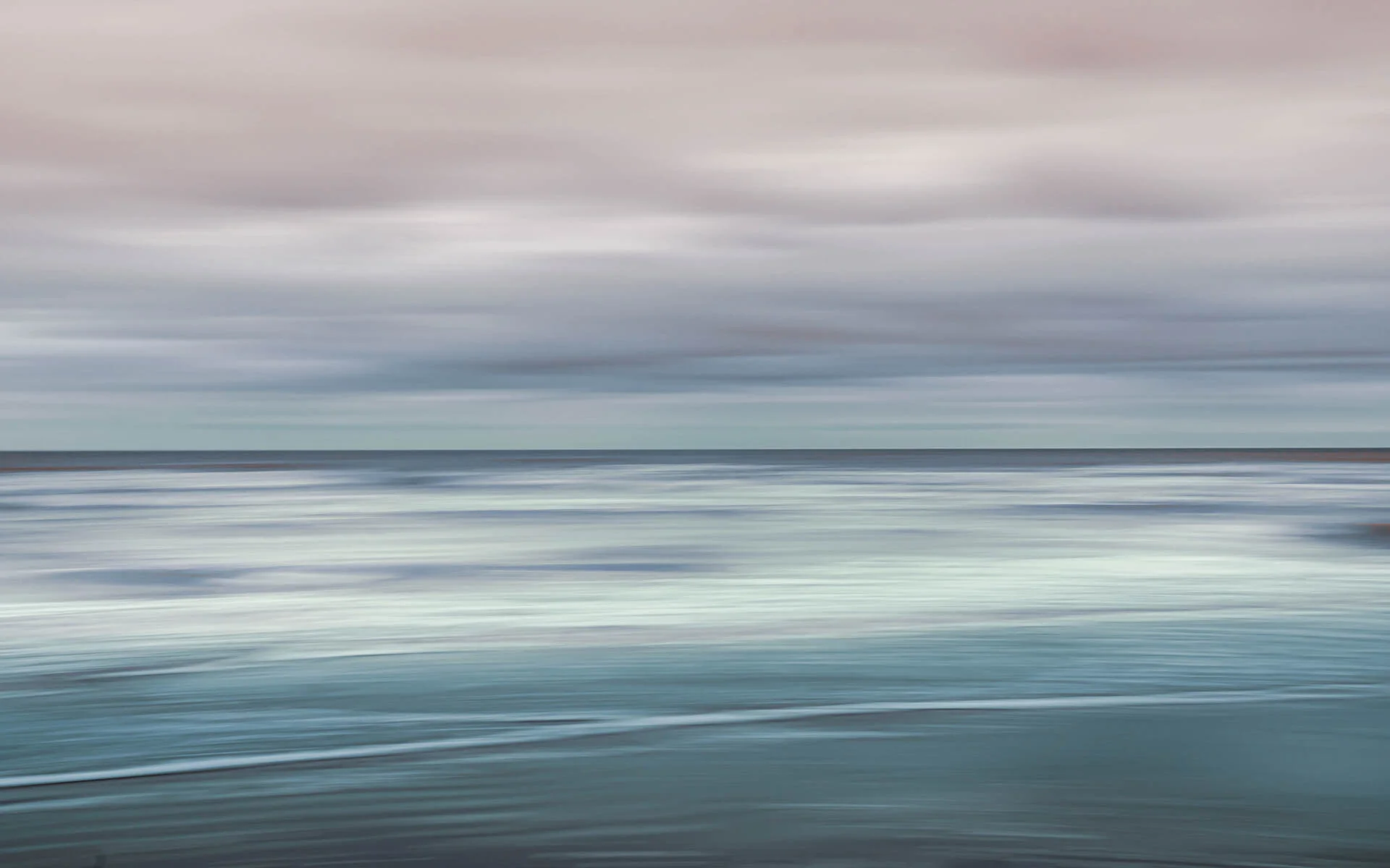 Abstract seascape with blurry ocean waves and cloudy sky.