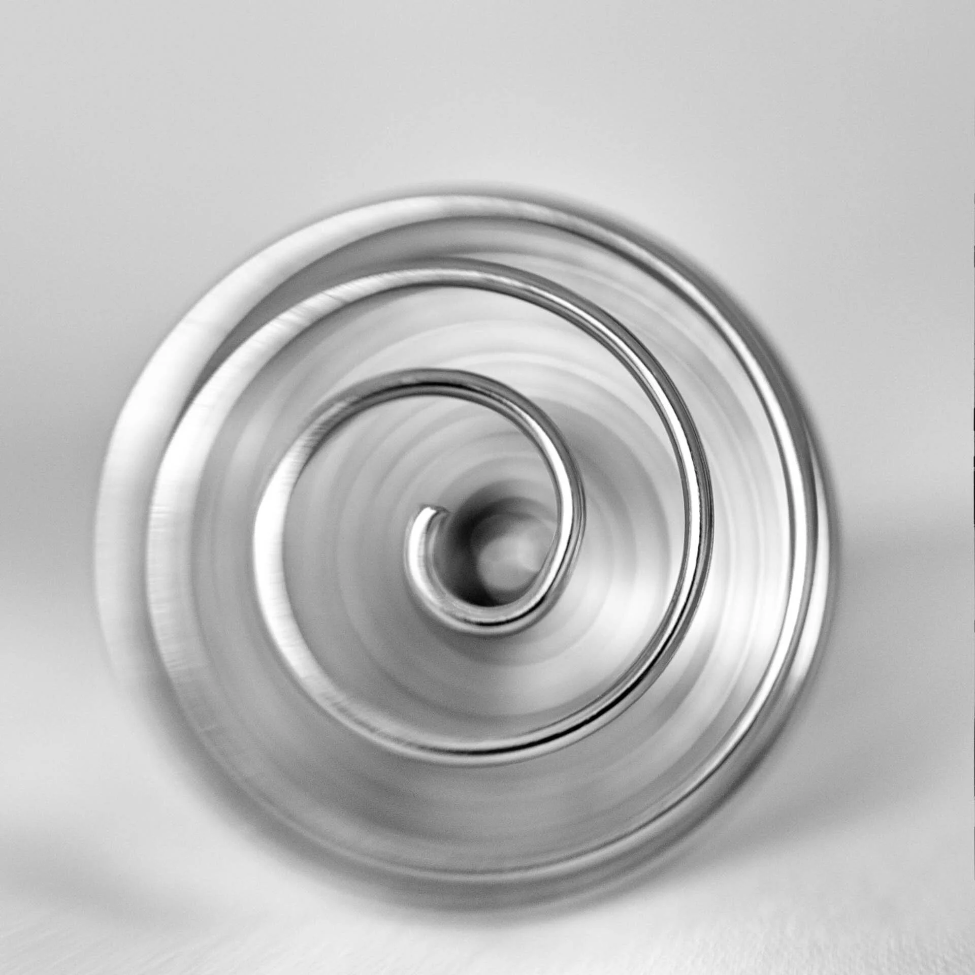 Close-up of a shiny metal spiral against a light background.