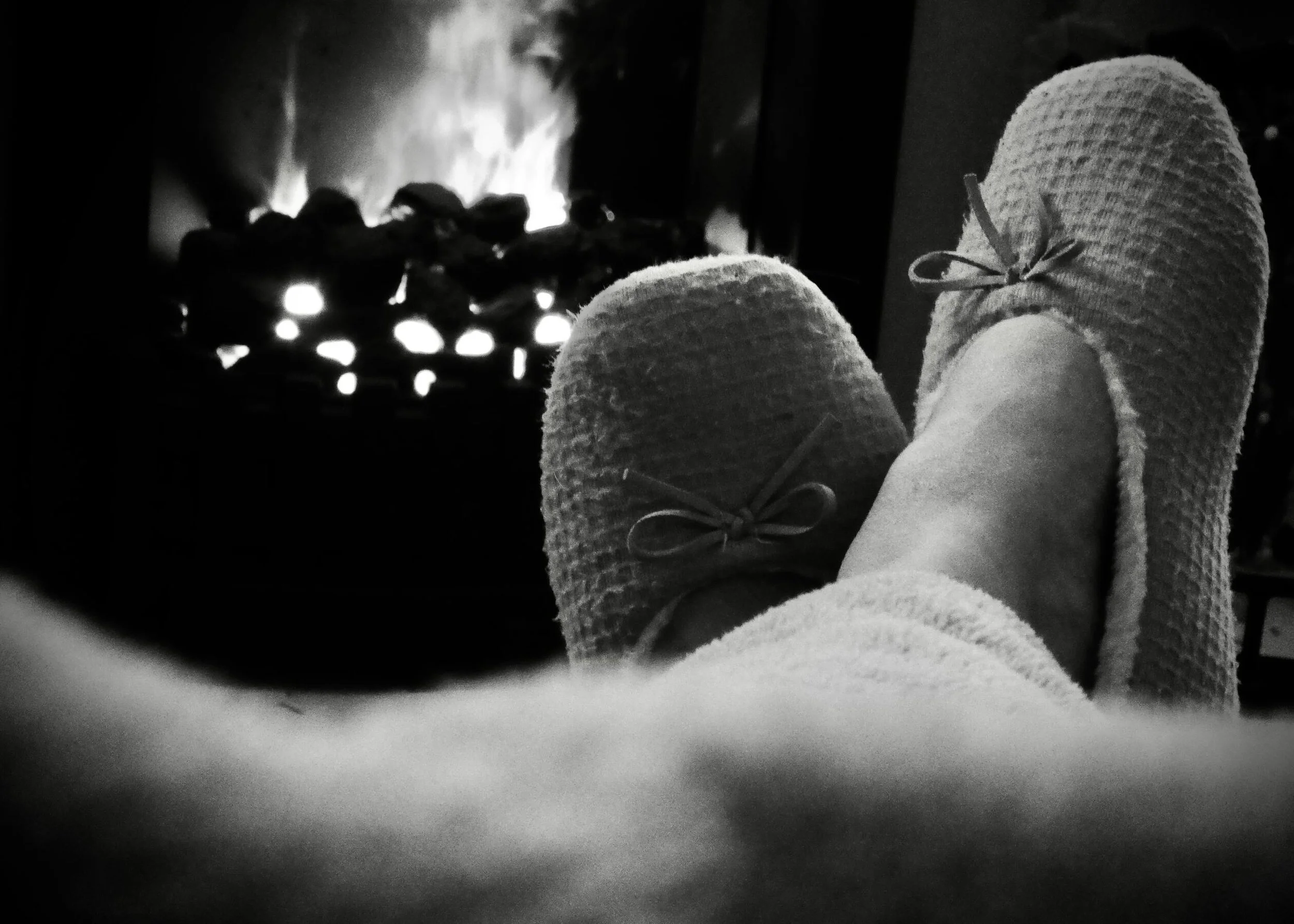 Person wearing cozy slippers relaxing in front of a fireplace