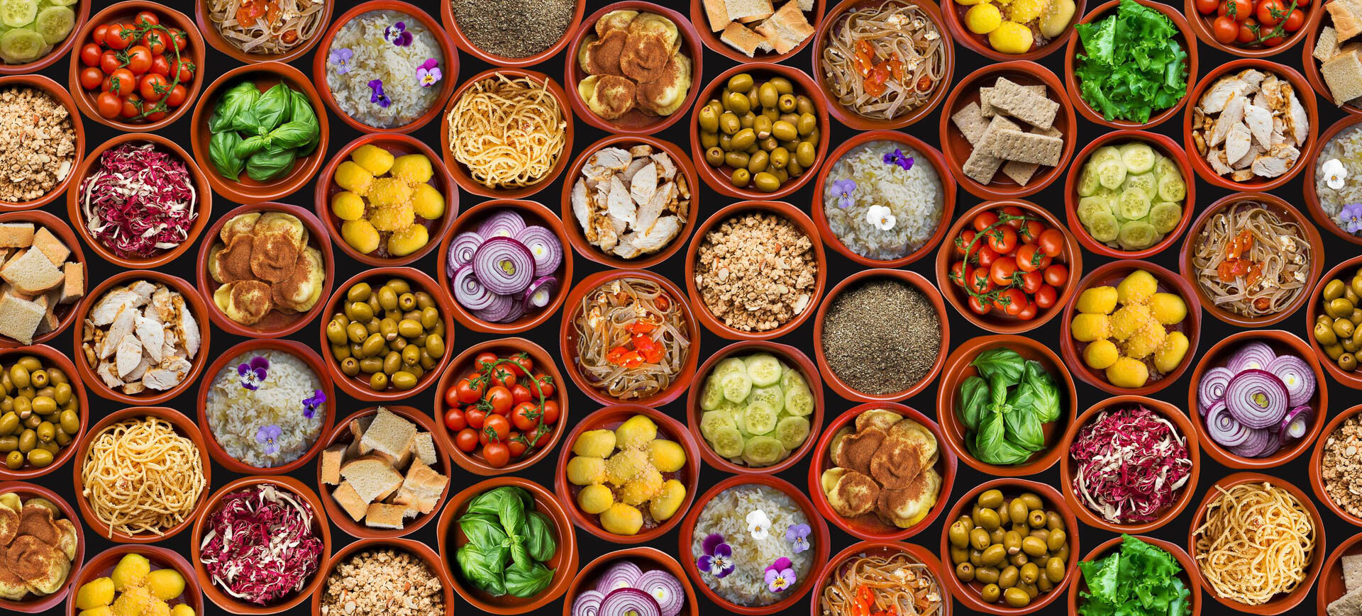 Various bowls of food including pasta, rice, cherry tomatoes, basil, bread, olives, sliced red onions, gnocchi, cucumber slices, shredded chicken, and mixed greens, arranged in a grid pattern.