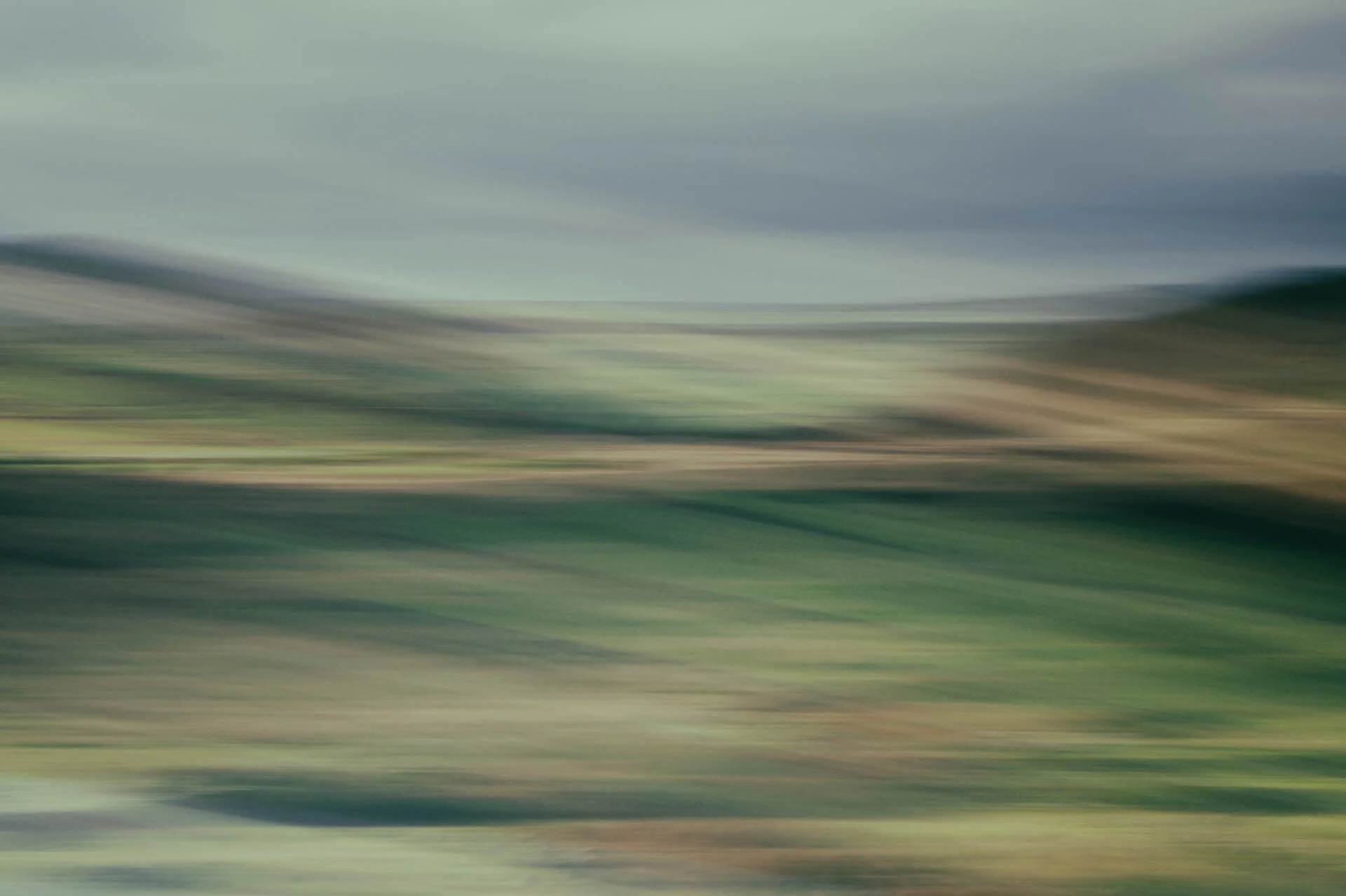 Abstract motion blur of green and brown landscape with cloudy sky
