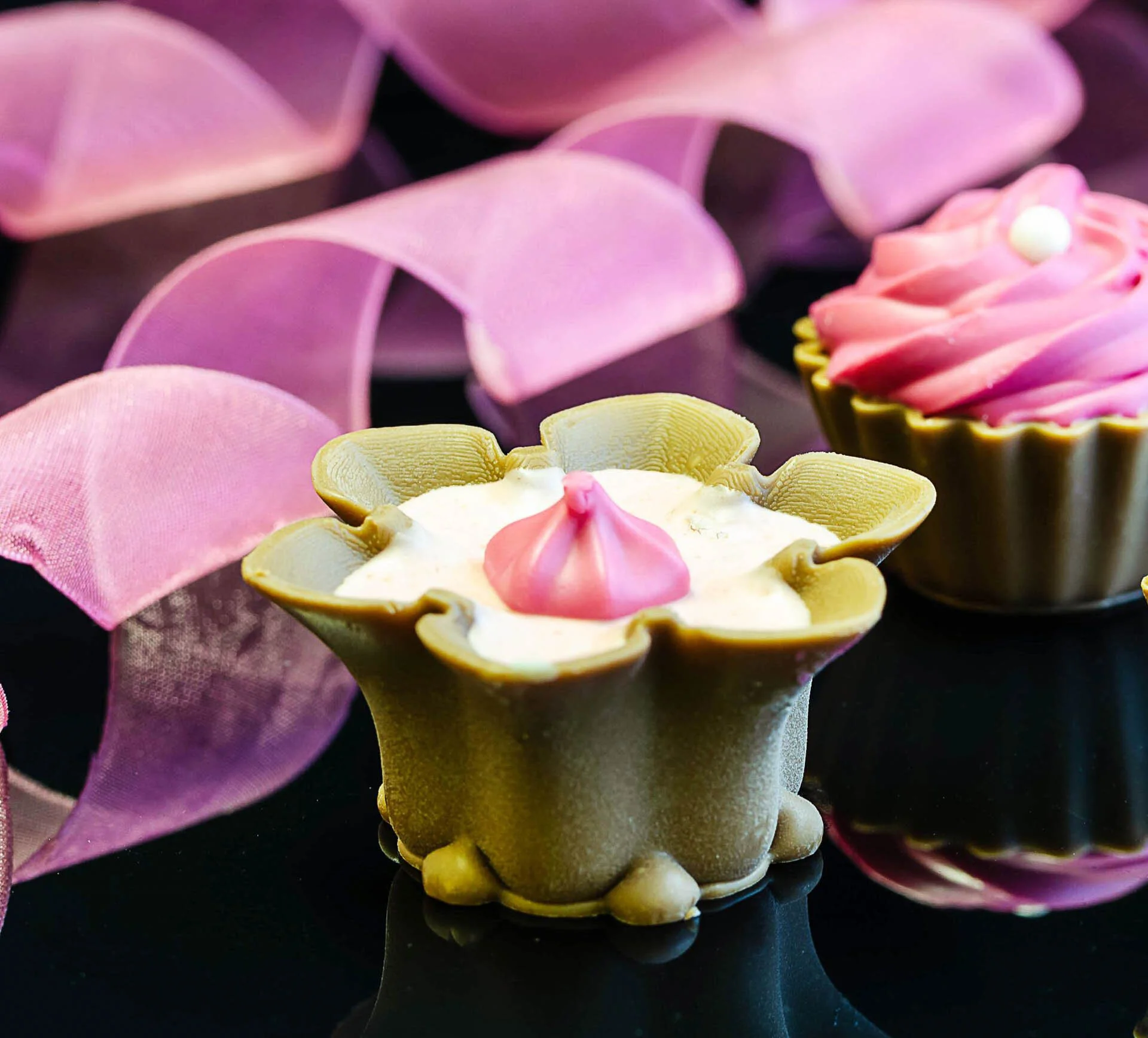 Decorative chocolates with pink frosting and ribbon