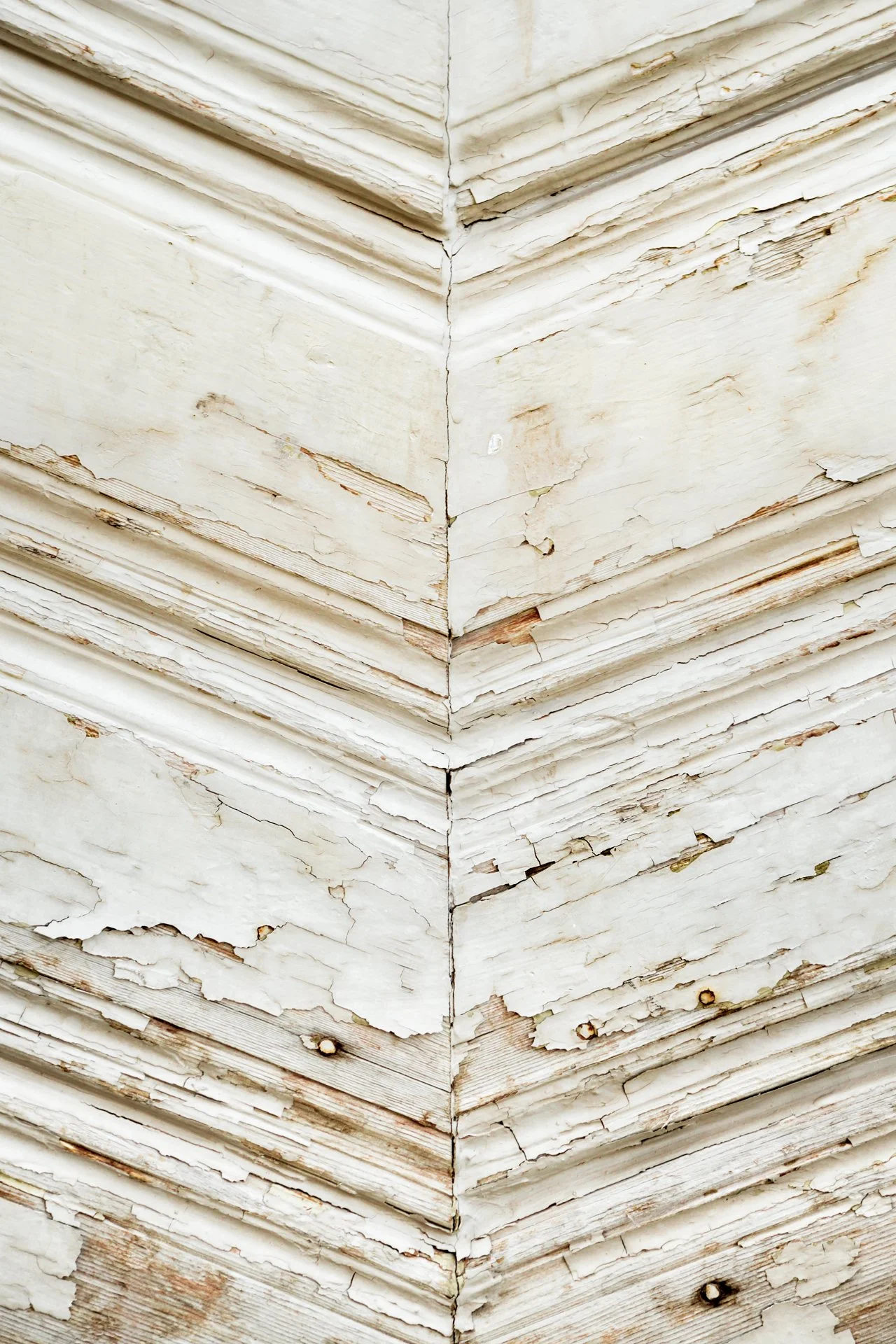 Weathered wooden surface with peeling white paint and detailed textures.
