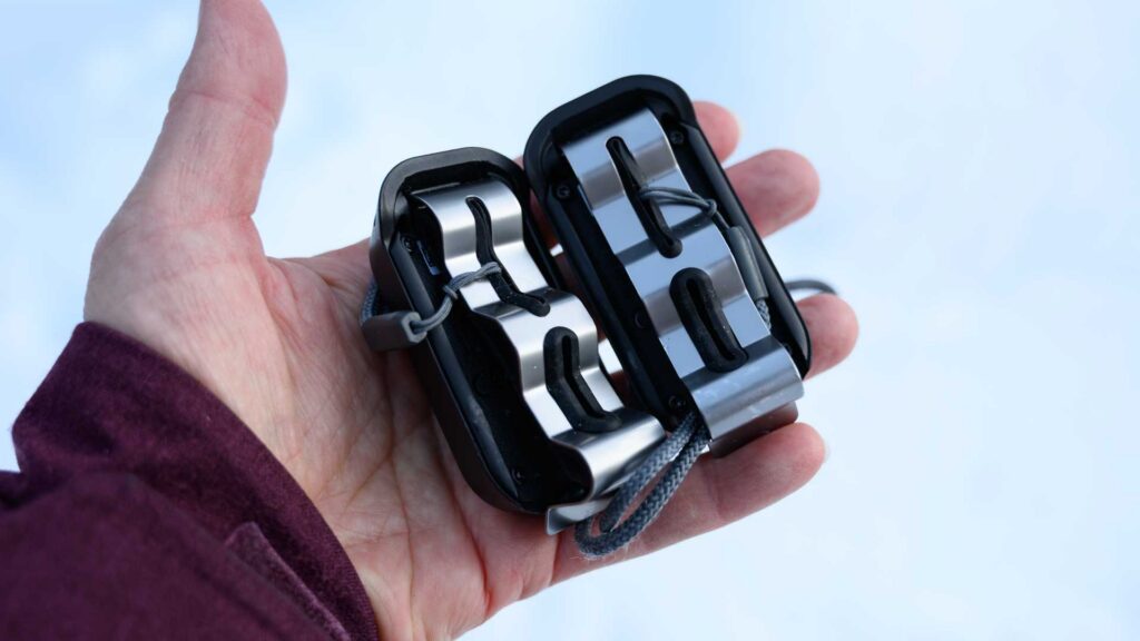 Underside of Carv foot sensors resting in a palm, showing curved metal plates and attached cords.